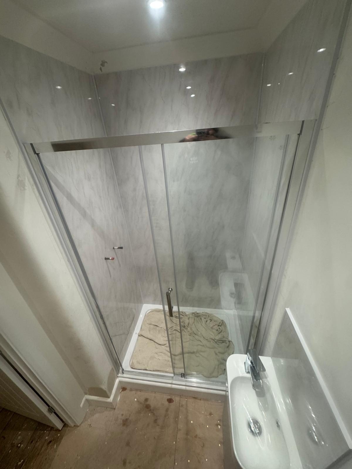 Sliding shower enclosure with marble-effect wall panels in a compact bathroom