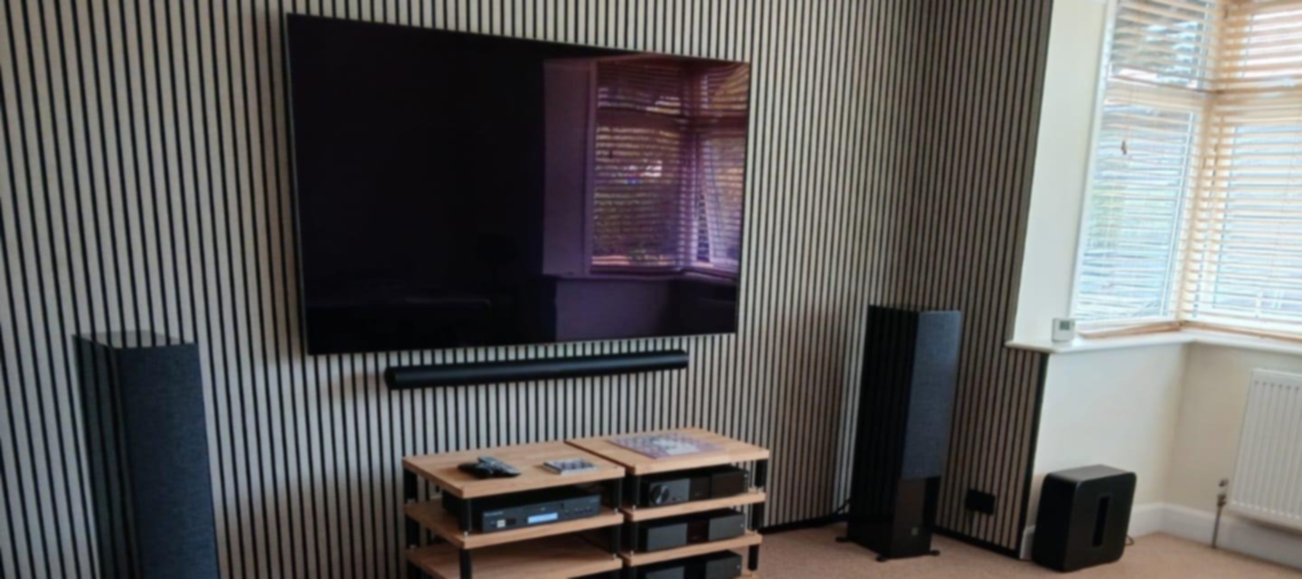 Slatted acoustic panel feature wall behind a wall-mounted TV and hi-fi, cladding in West Sussex