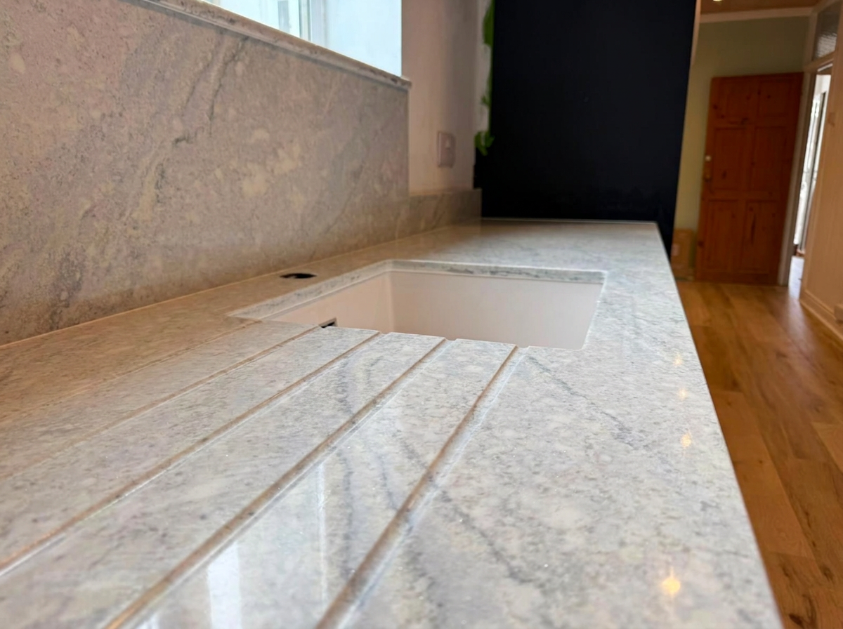 Undermount sink fitted in a granite worktop with drainer grooves, plumbing in West Sussex