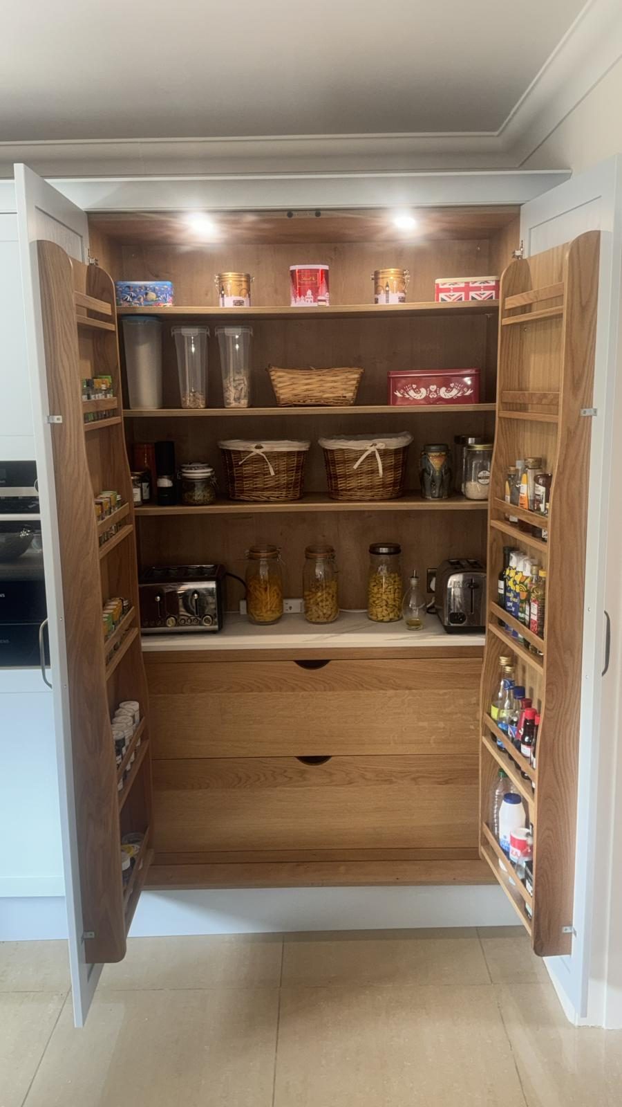 Oak larder pantry unit with spice-rack doors and deep drawers in a fitted kitchen