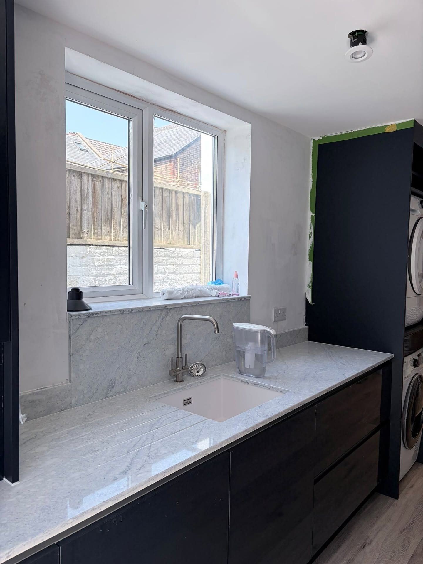 Granite worktop with undermount sink and drainer grooves under a kitchen window