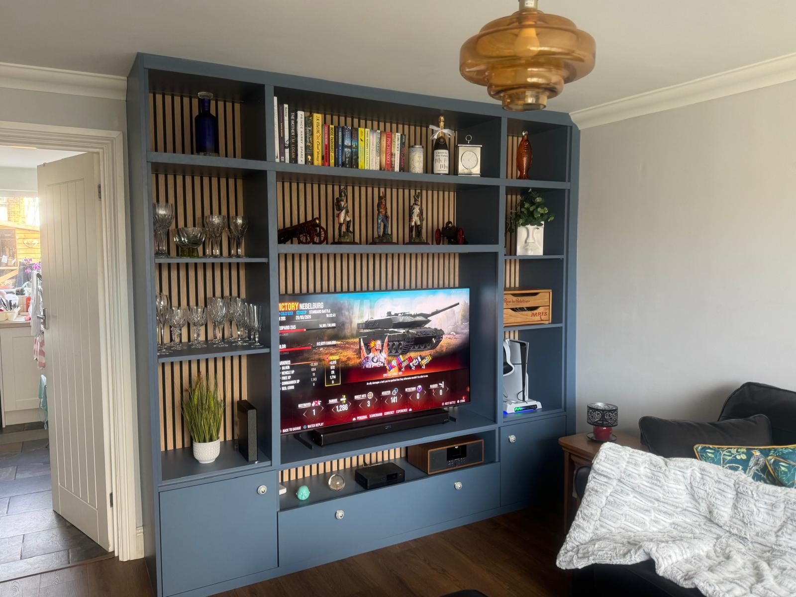 Bespoke blue media wall with slatted oak panels, shelving and TV recess