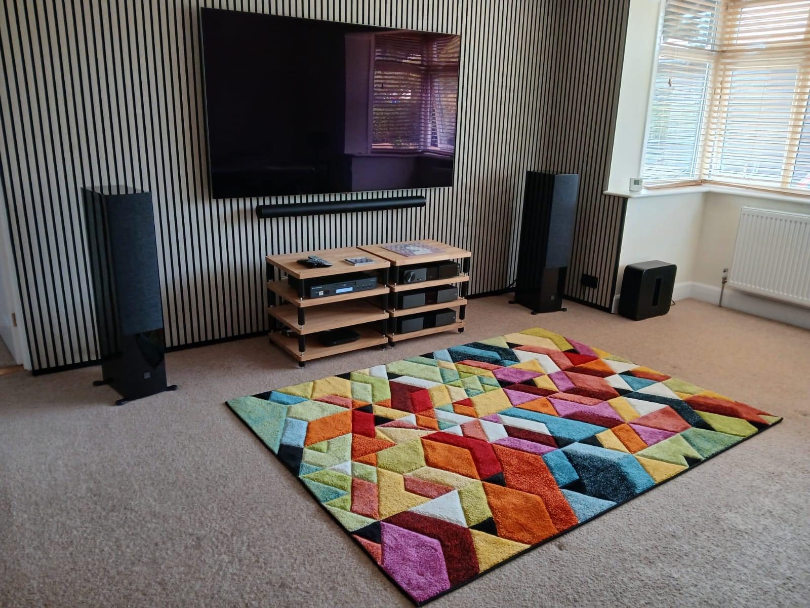 Slatted acoustic wall panelling behind a wall-mounted TV in a living room